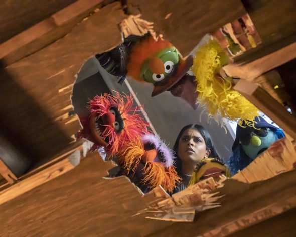 Seen from below, the Electric Mayhem an Nora stare through a hole that has been broken through the floor