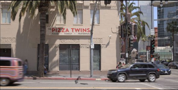 A sign on a storefront reads: THE PIZZA TWINS - FOOD - FAMILY - FRATERNAL