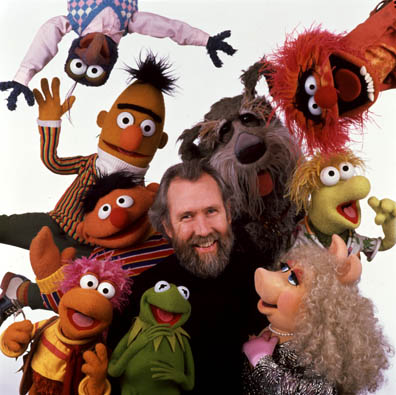 Jim Henson surrounded by Muppets, smiling.