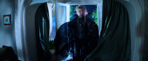 Screenshot from Labyrinth: Jareth appears in Sarah's house in a flowing cape.