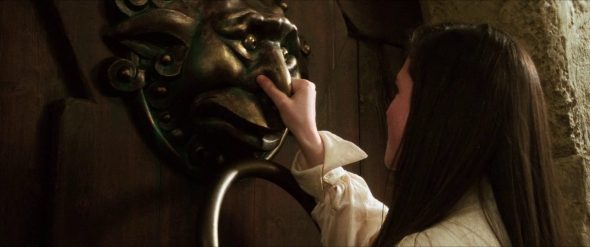 Screenshot from Labyrinth: Sarah holds a door knocker's nose.