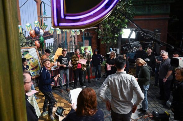 Behind the scenes on the set of the Sesame Street episode "Happy Bert Day", where the cast in crew is standing in a big circle.